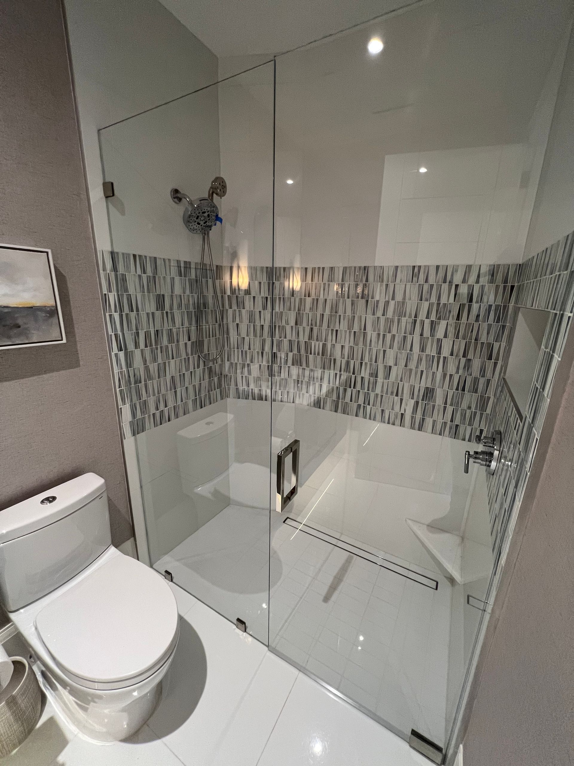 Modern bathroom with a glass shower, toilet, and tile.