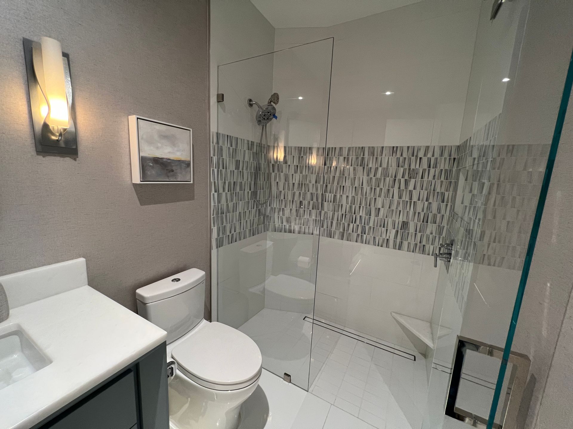 Modern bathroom with gray walls, glass shower, white toilet, and gray vanity.