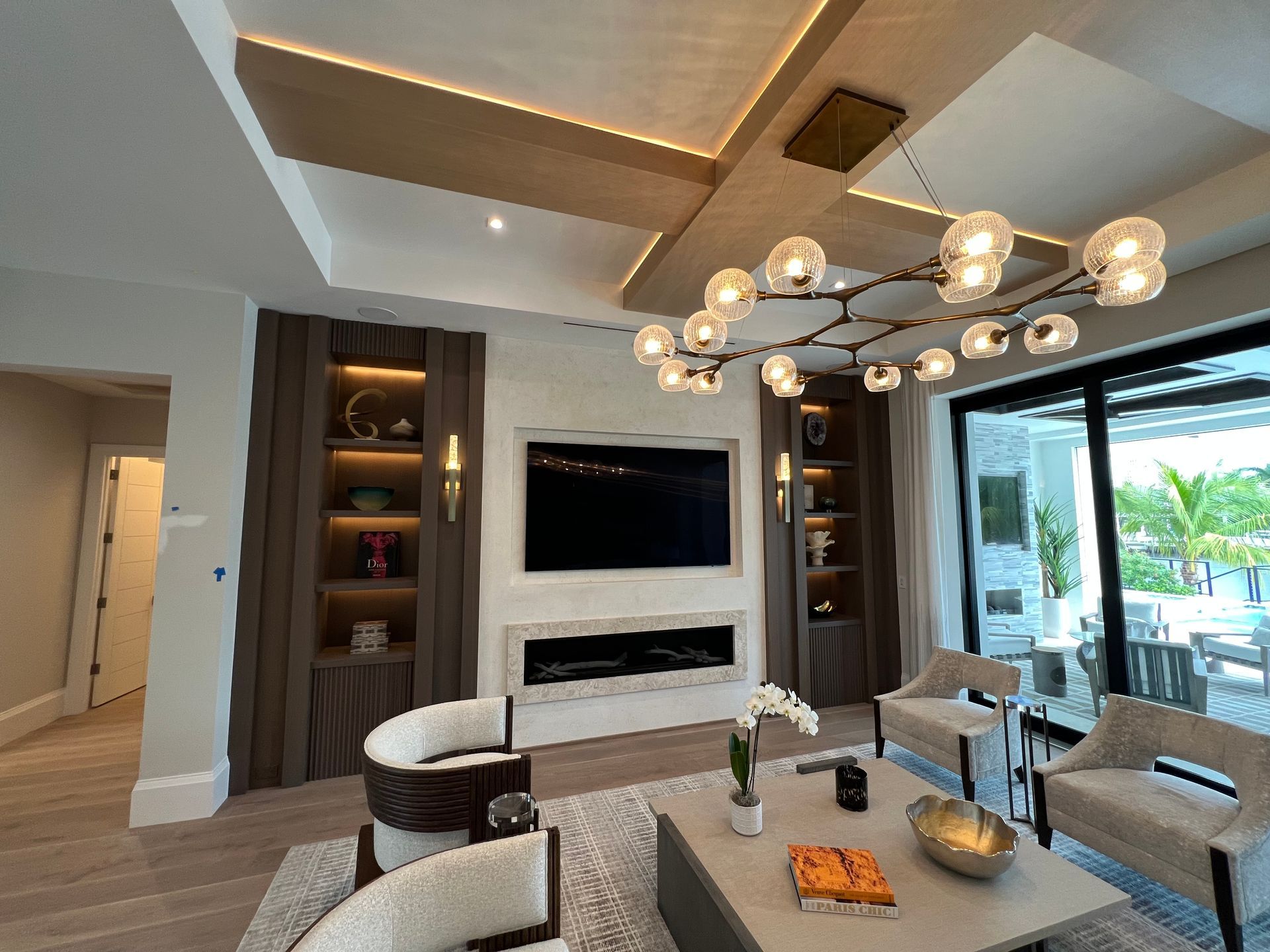 Living room with TV, fireplace, chandelier, and modern furniture.