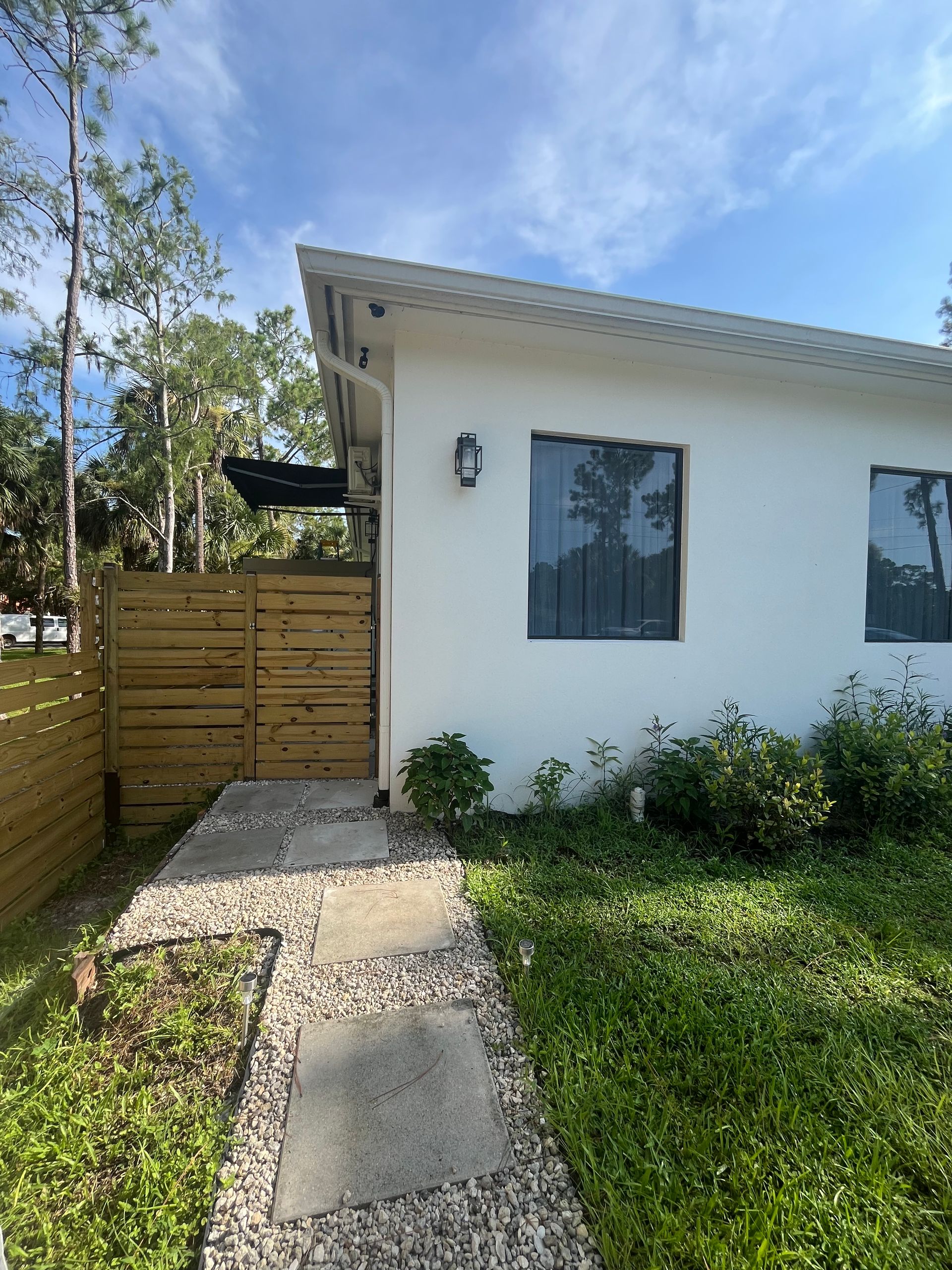 White house with a sloped roof, wooden fence, and stone path.
