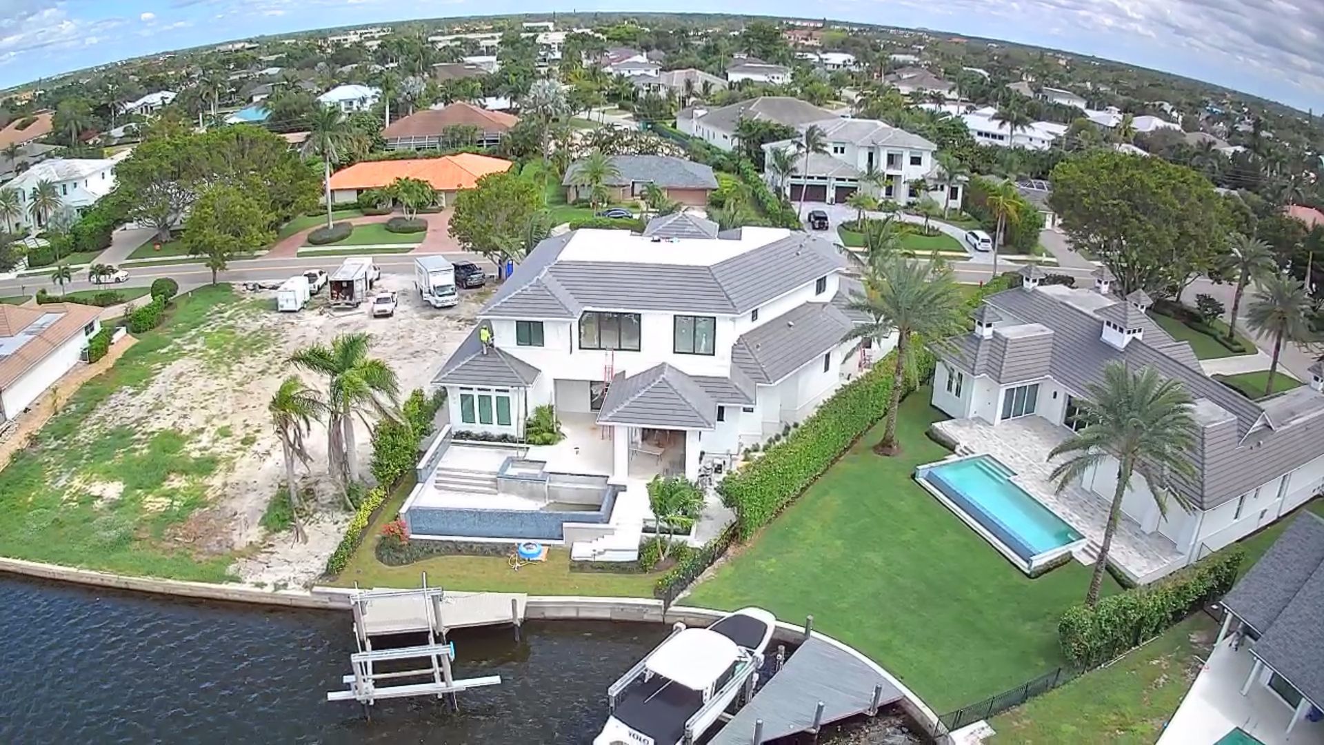 Aerial view of luxury homes with a pool, dock, and canal in a coastal community.