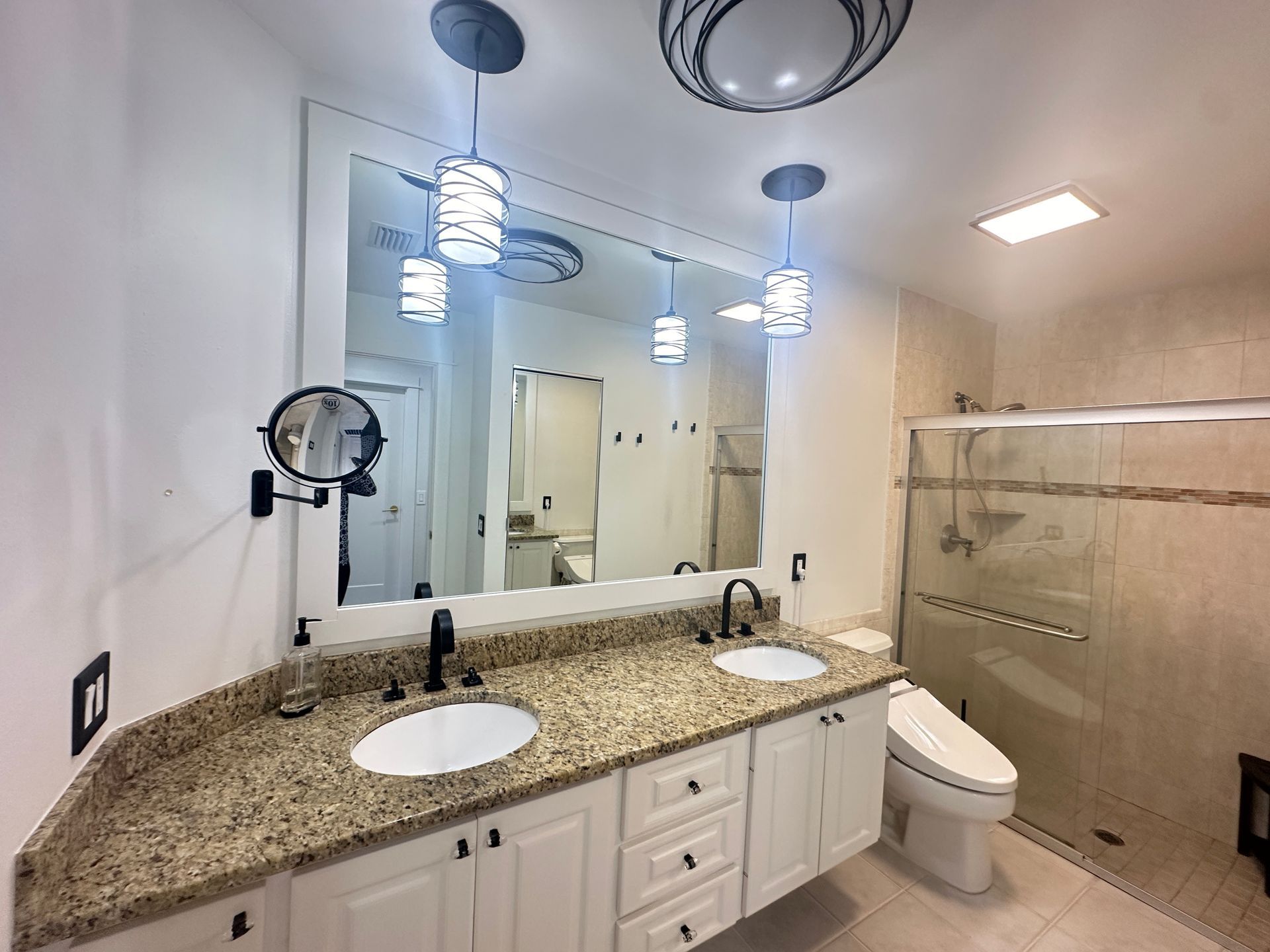 Bathroom with a double vanity, large mirror, and a glass-enclosed shower.