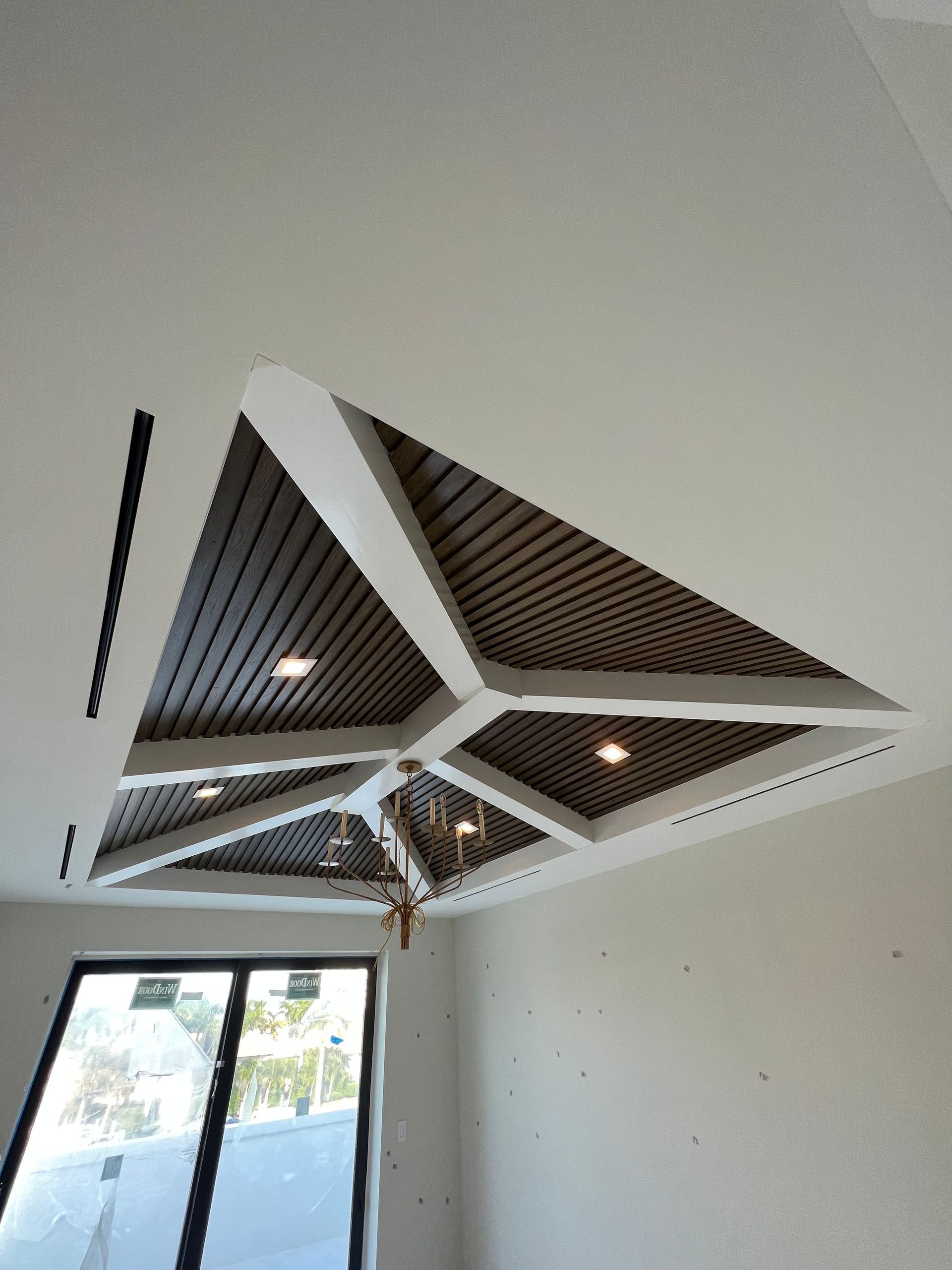 Geometric ceiling with recessed wood panels, inset lighting, and white trim.