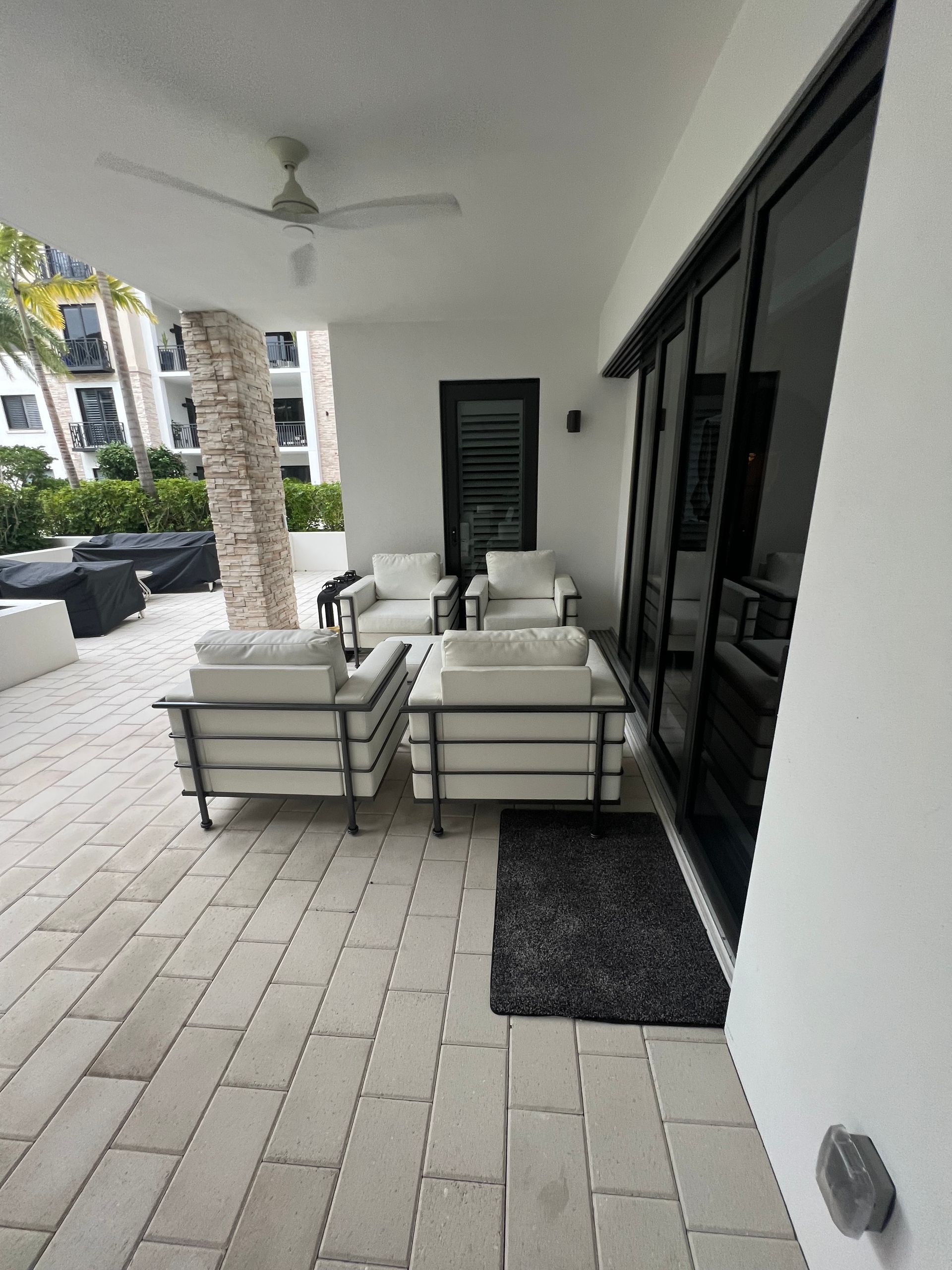 Outdoor patio with white furniture, black doors, and brick flooring.