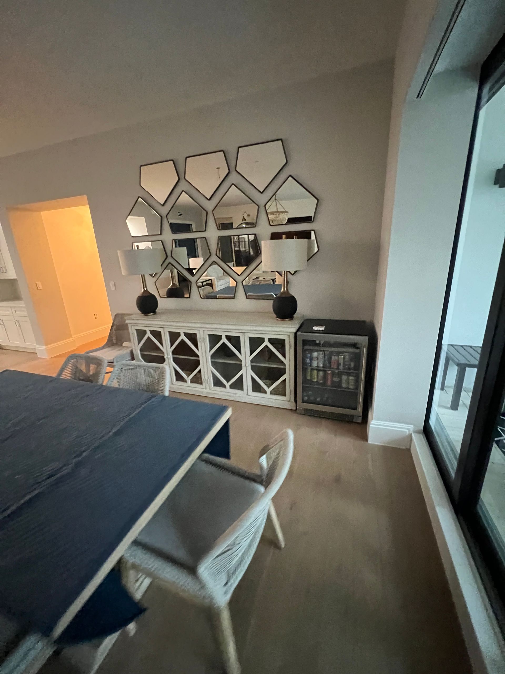 White dining room with mirrored wall decor, sideboard, and a mini-fridge.
