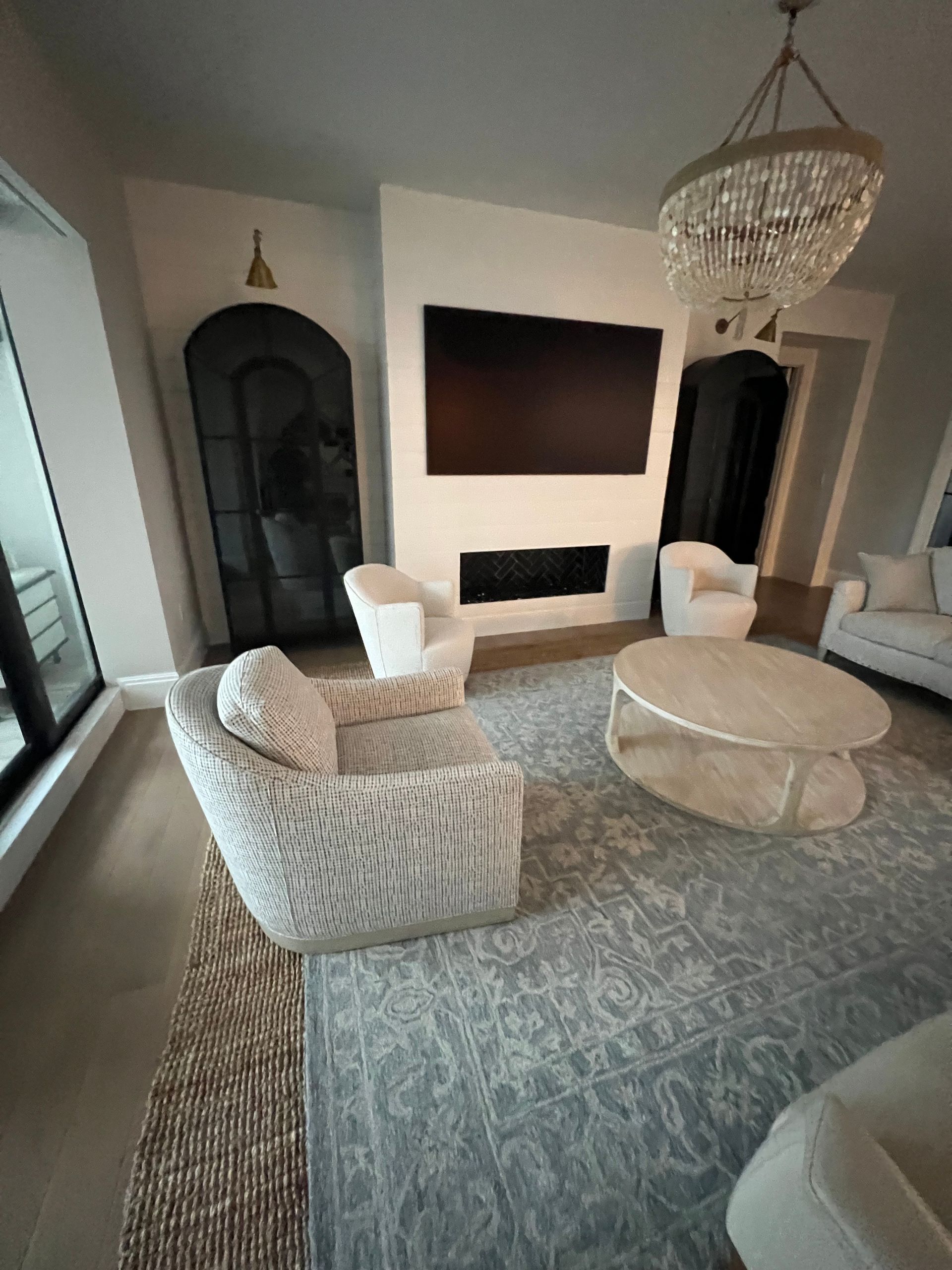 Living room with modern furniture: zebra-print chair, rug, fireplace, chandelier.