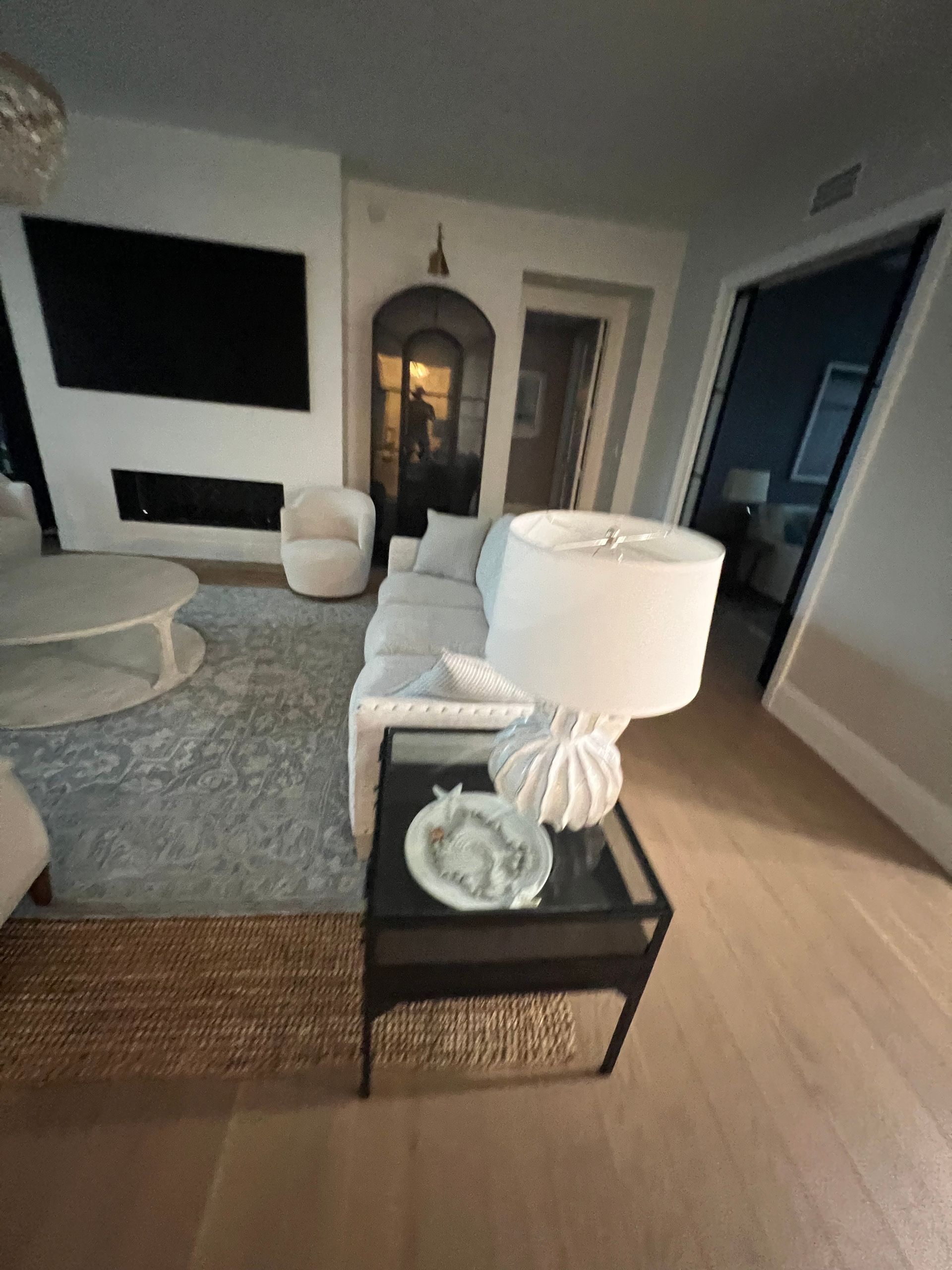 Living room with white couch, rug, lamp, fireplace, and TV; bright and airy.