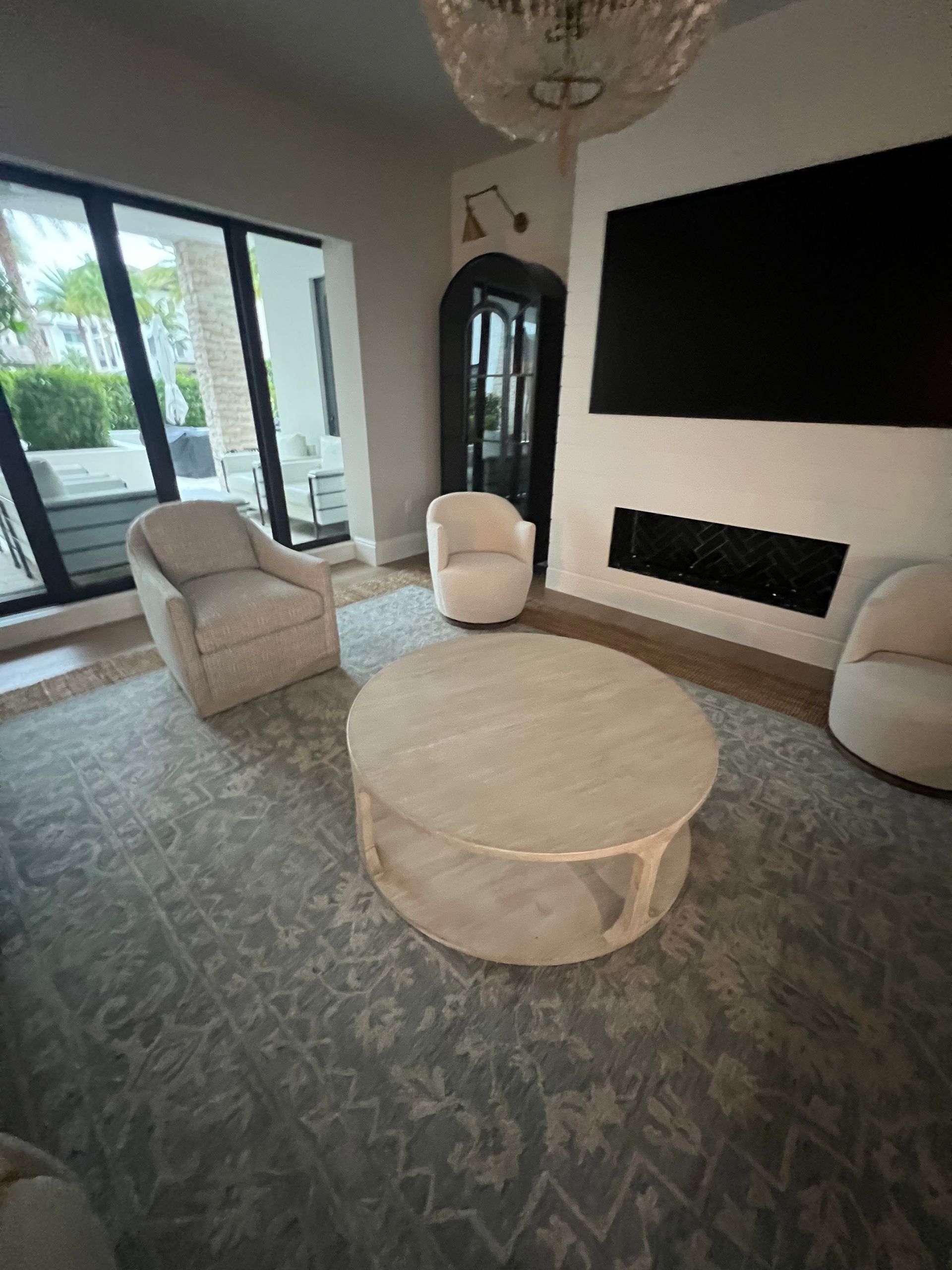 Living room with white chairs, round coffee table, fireplace, TV, and large rug.