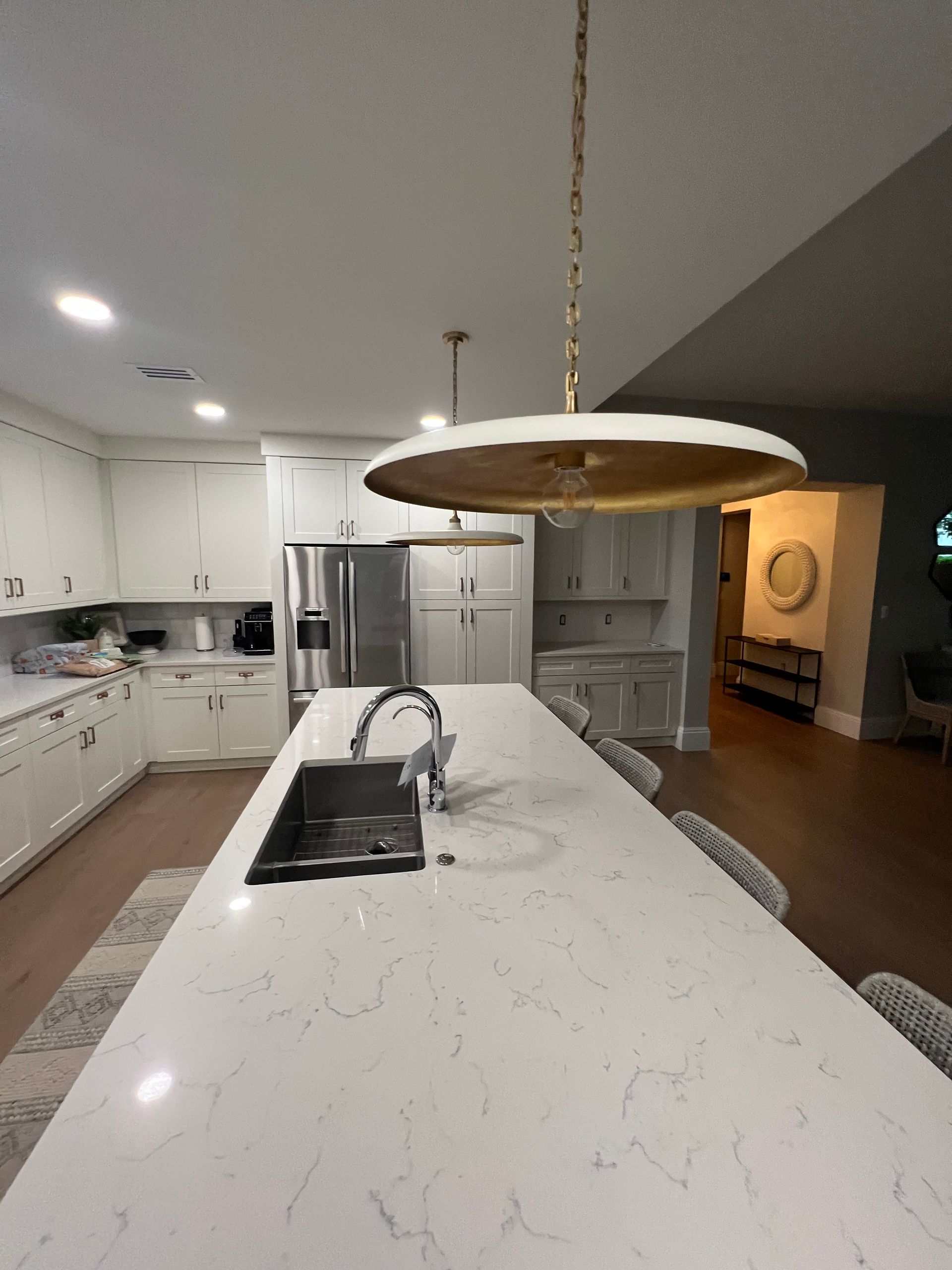 Modern kitchen with a large island, white cabinets, and gold pendant lights.