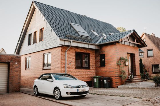 a white car is parked in front of a brick house .