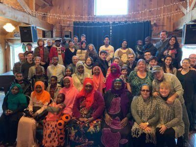 Group photo of diverse people posing inside a building. Some are wearing headscarves.