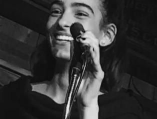 Woman smiling, holding a microphone. Black and white photo.