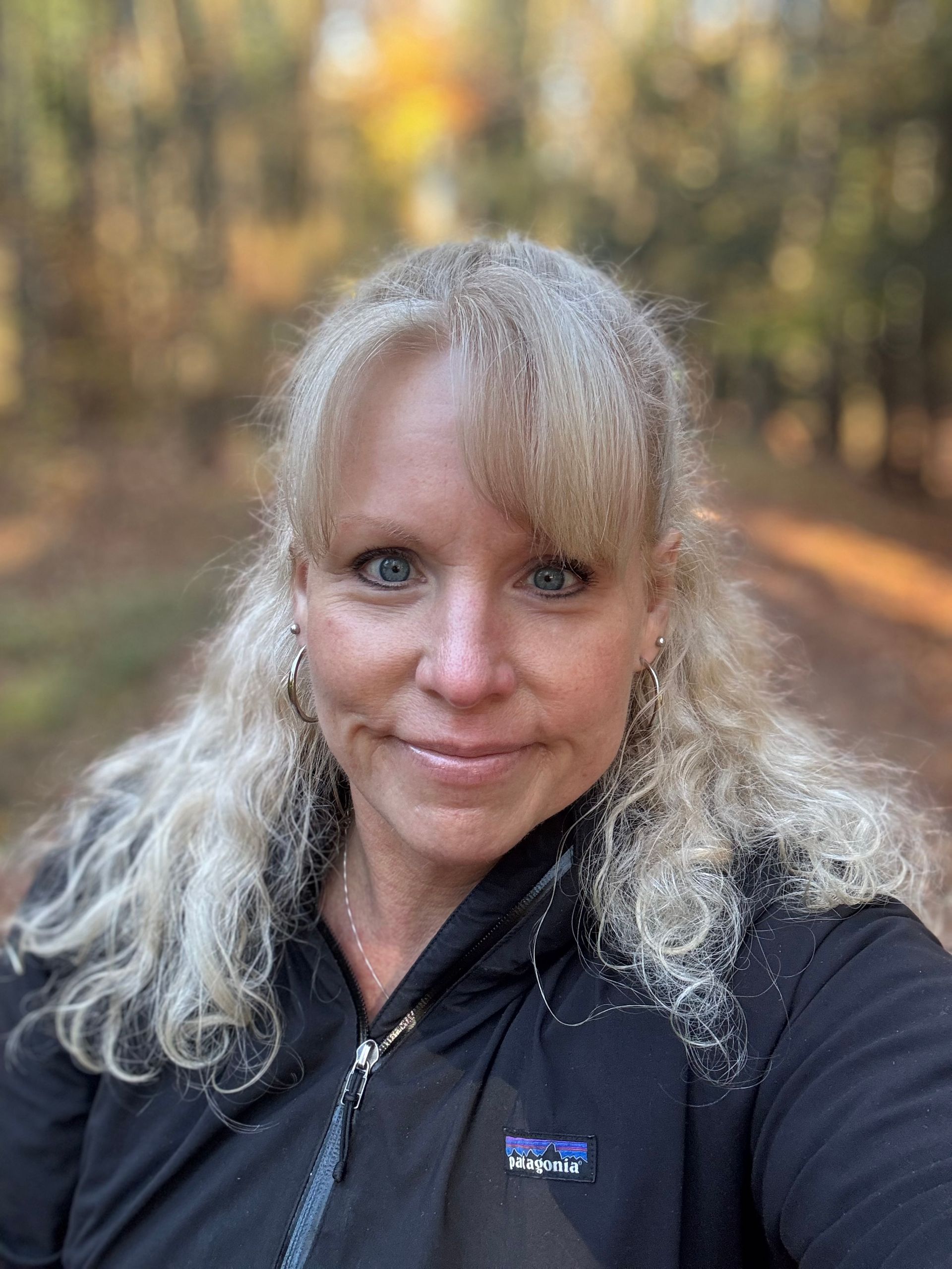 Man wearing glasses and a red patterned tie, smiling in a suit jacket.