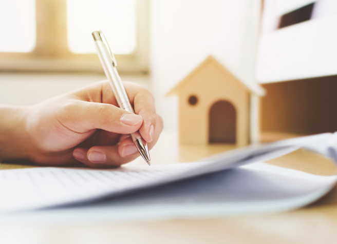 Person signing a will with a small house model and documents — estate planning checklist