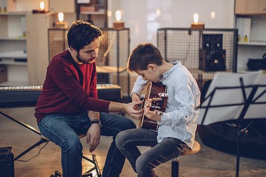 man teaching child how to play guitar