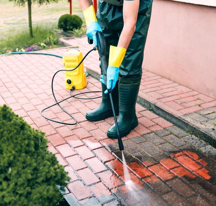 A Man Is Using A High Pressure Washer To Clean A Brick Sidewalk — TCM Carpet & Cleaning In Koongal, QLD