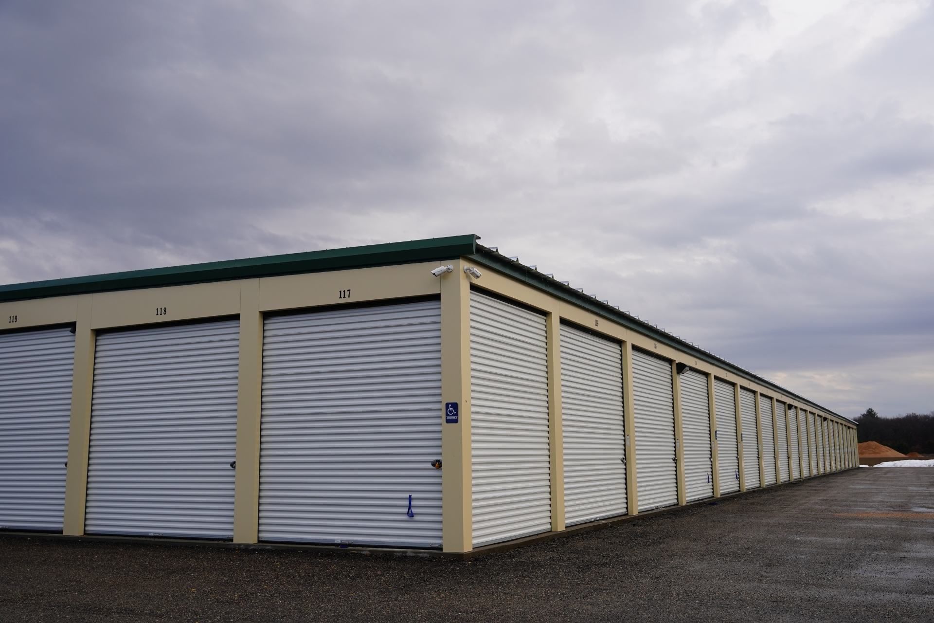 Storage units with white doors under a cloudy sky.