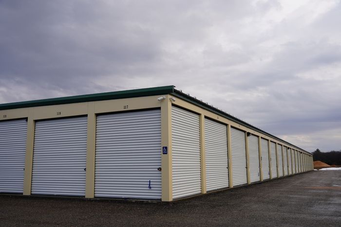 Storage units with white doors under a cloudy sky.