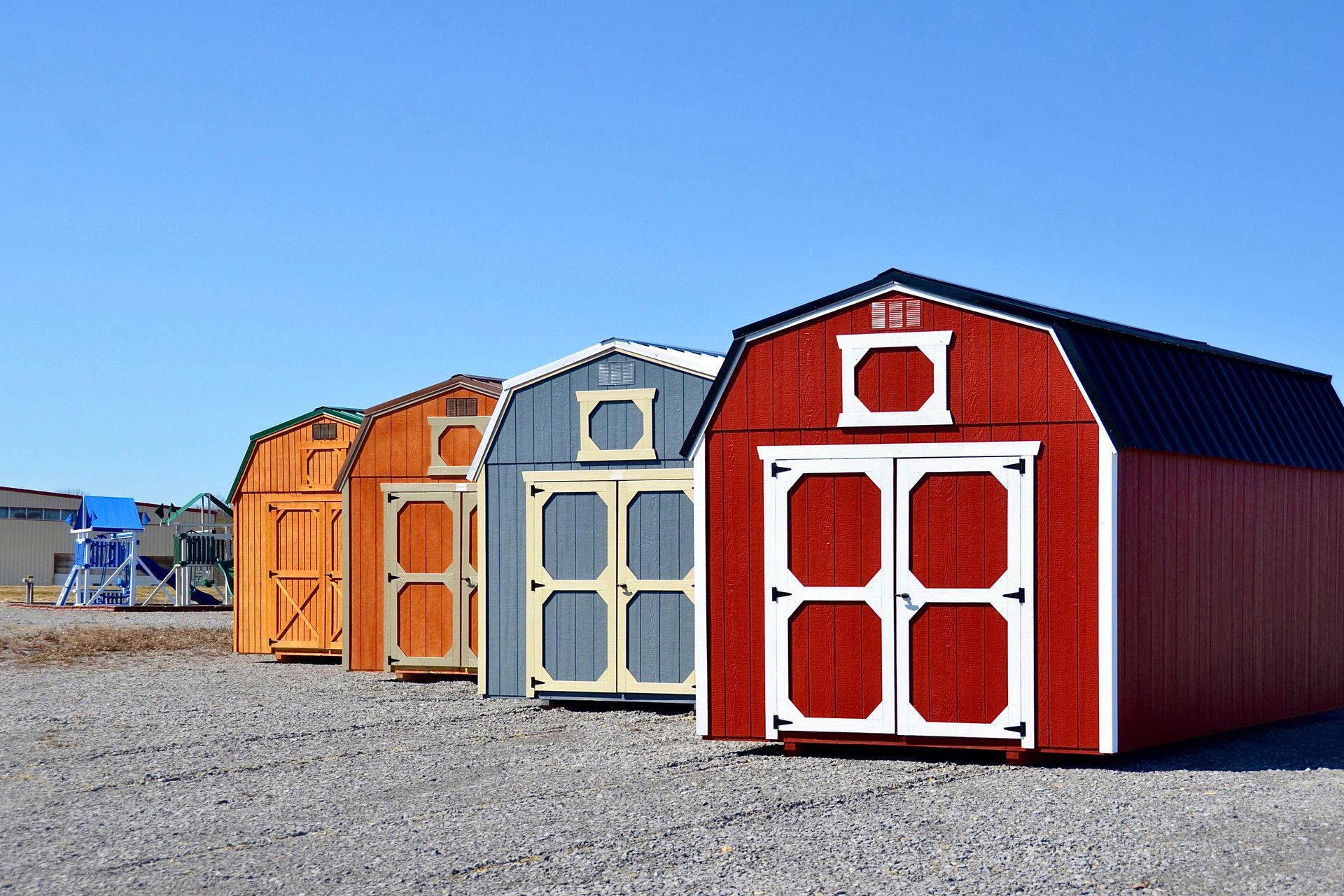 Row of colorful storage sheds in various hues against a blue sky.
