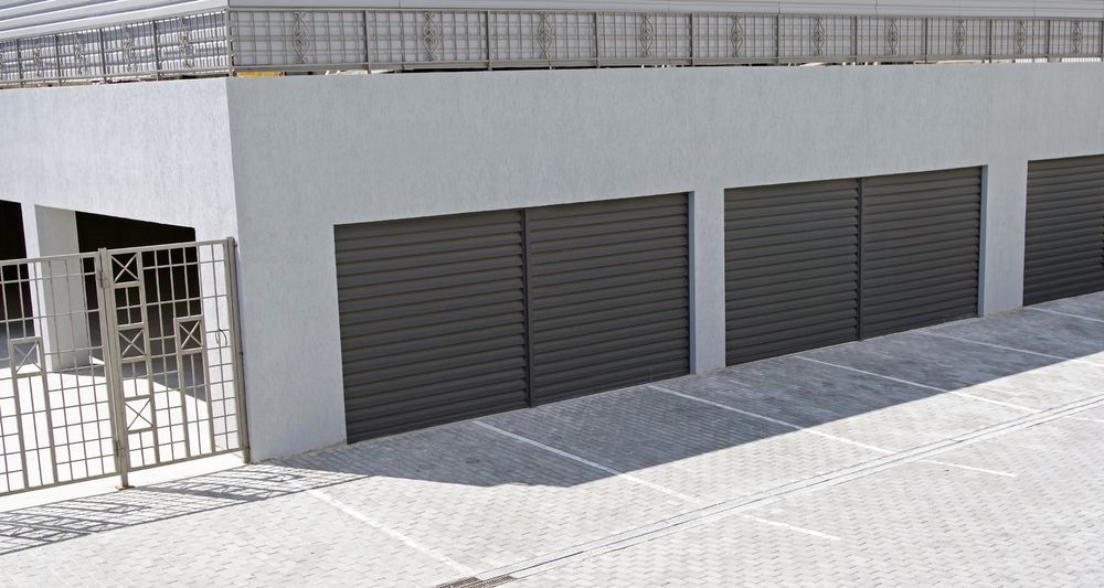 White garage door partially open, mounted on a white wall, with metal track extending overhead.