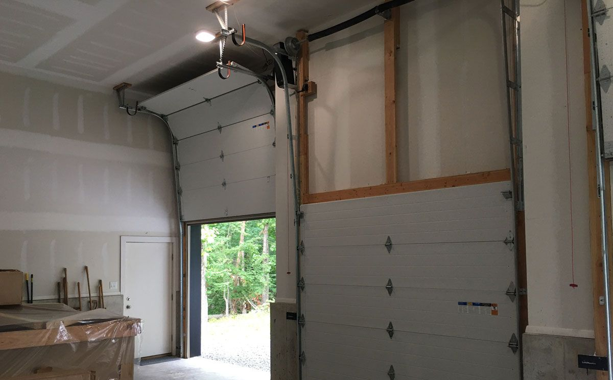 Interior of a warehouse with three closed loading dock doors and a gray floor.