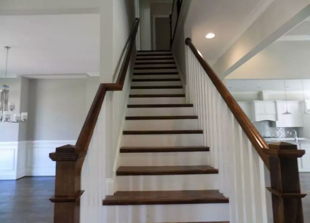 Wooden staircase with white risers and brown treads and handrails in a home.