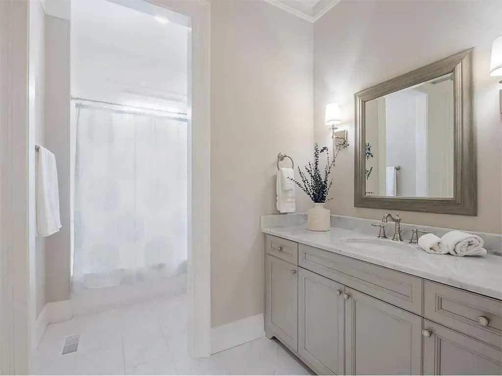 White bathroom with a shower, vanity, and mirror.