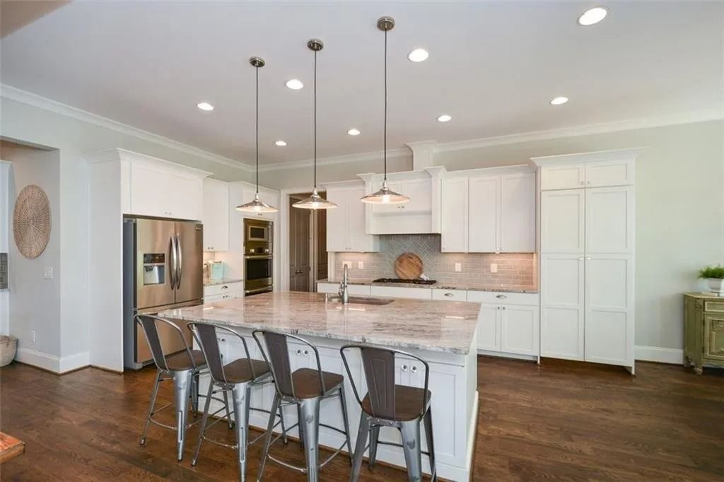 Bright kitchen with a large island, stainless steel appliances, and wood floors.