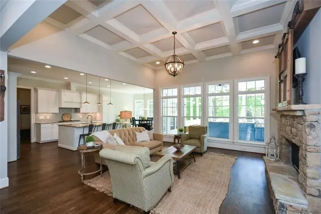 Spacious living room with fireplace, white walls, and dark wood floors; open to kitchen and dining areas.