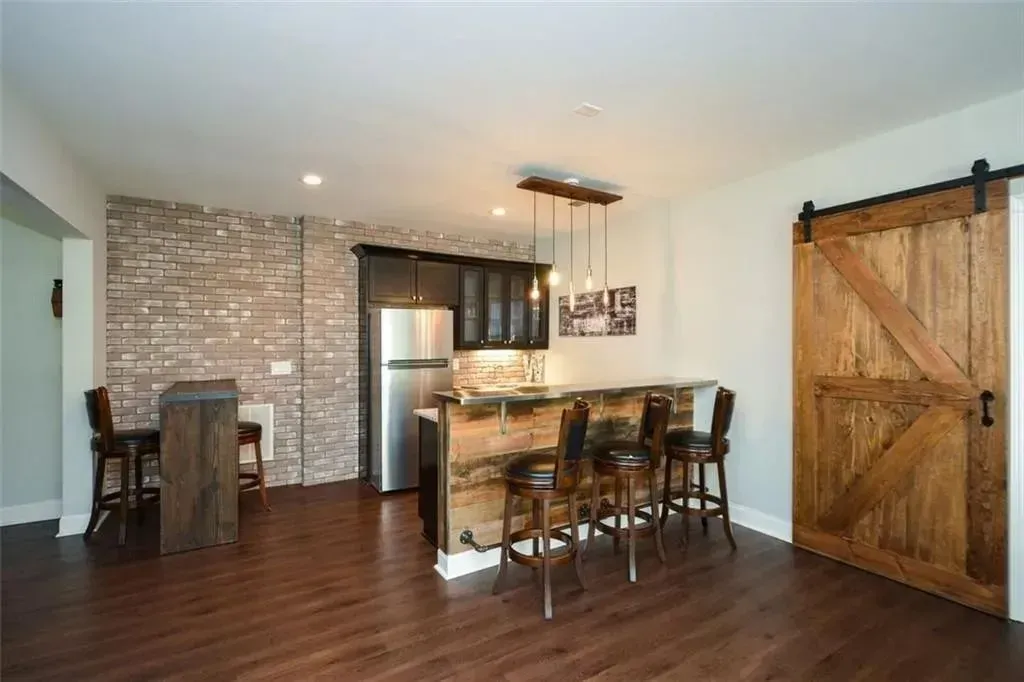 Bar with rustic wood accents, brick wall, dark cabinets, and sliding barn door.
