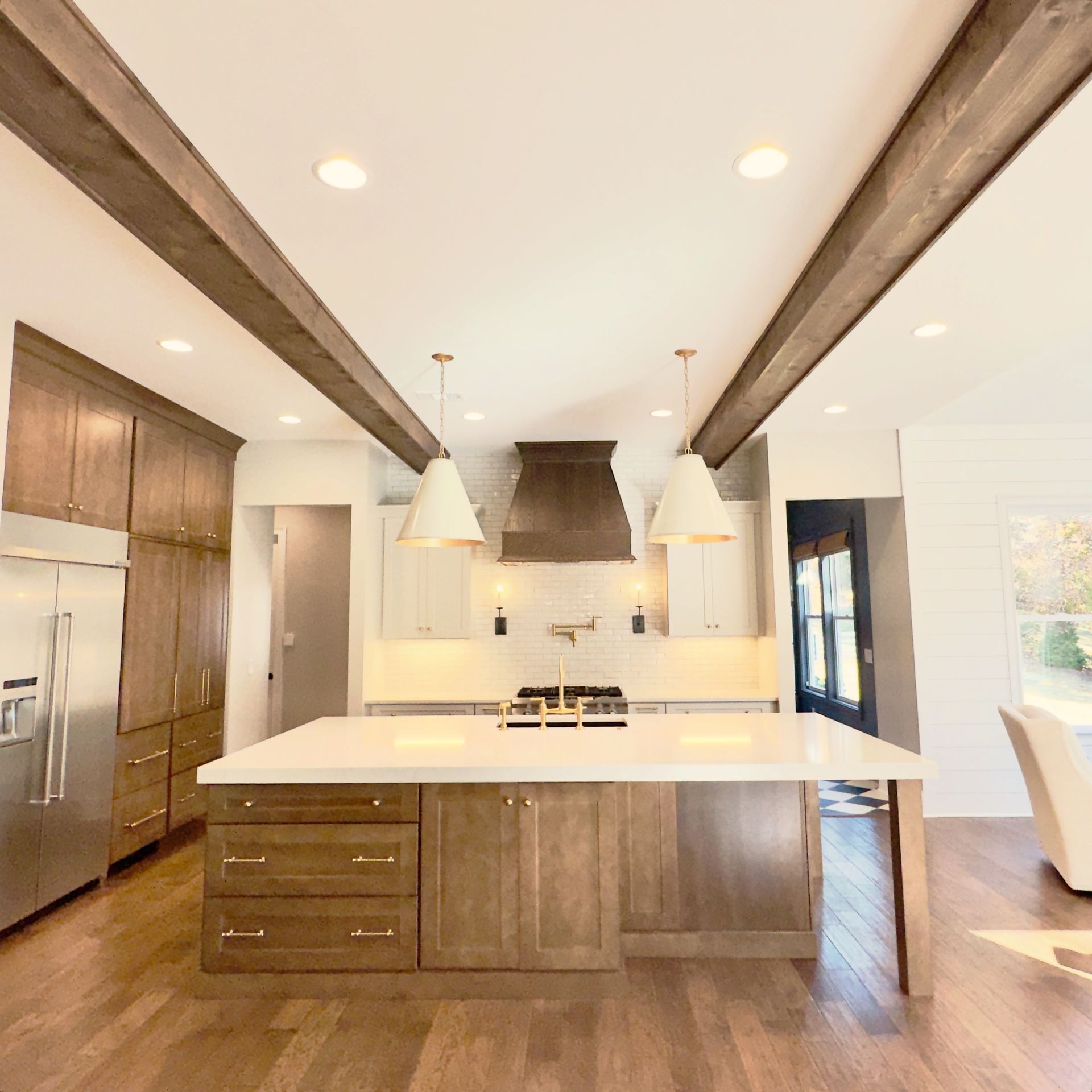 Kitchen with wooden beams, white countertops, stainless steel appliances, and wood cabinetry.