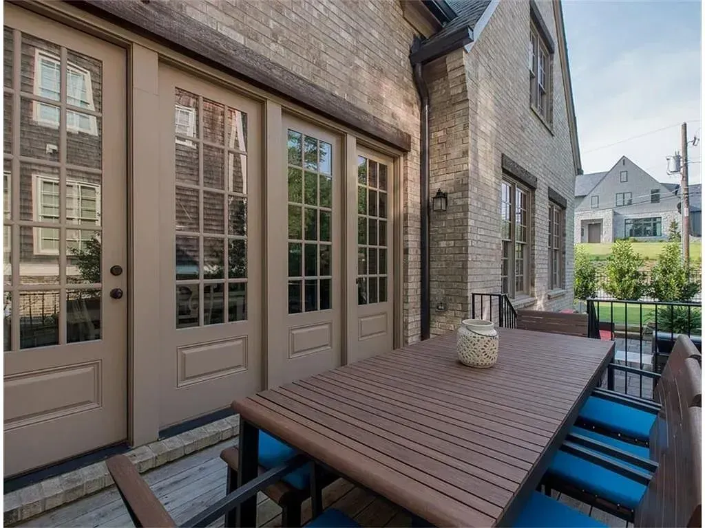 Outdoor patio with a brown table, chairs, and French doors on a brick building.