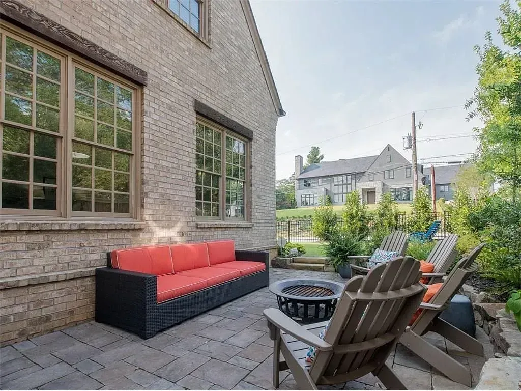 Patio with brick building, seating, fire pit, and trees.