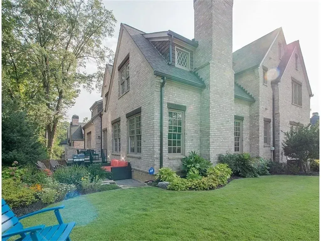 Brick house with a green lawn, garden, and blue chair.