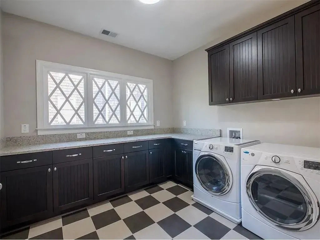 Laundry room with dark cabinets, white appliances, and a checkered floor.
