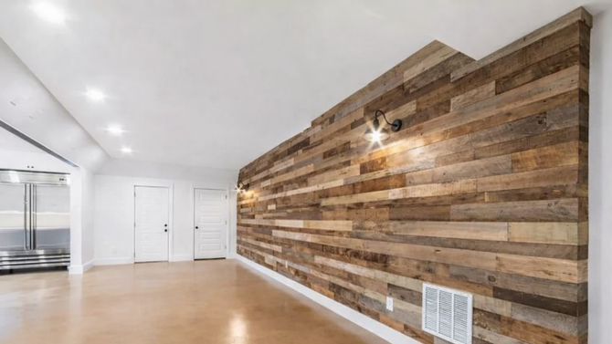 A wide, bright room featuring a long accent wall covered in rustic, multicolored reclaimed wooden planks.