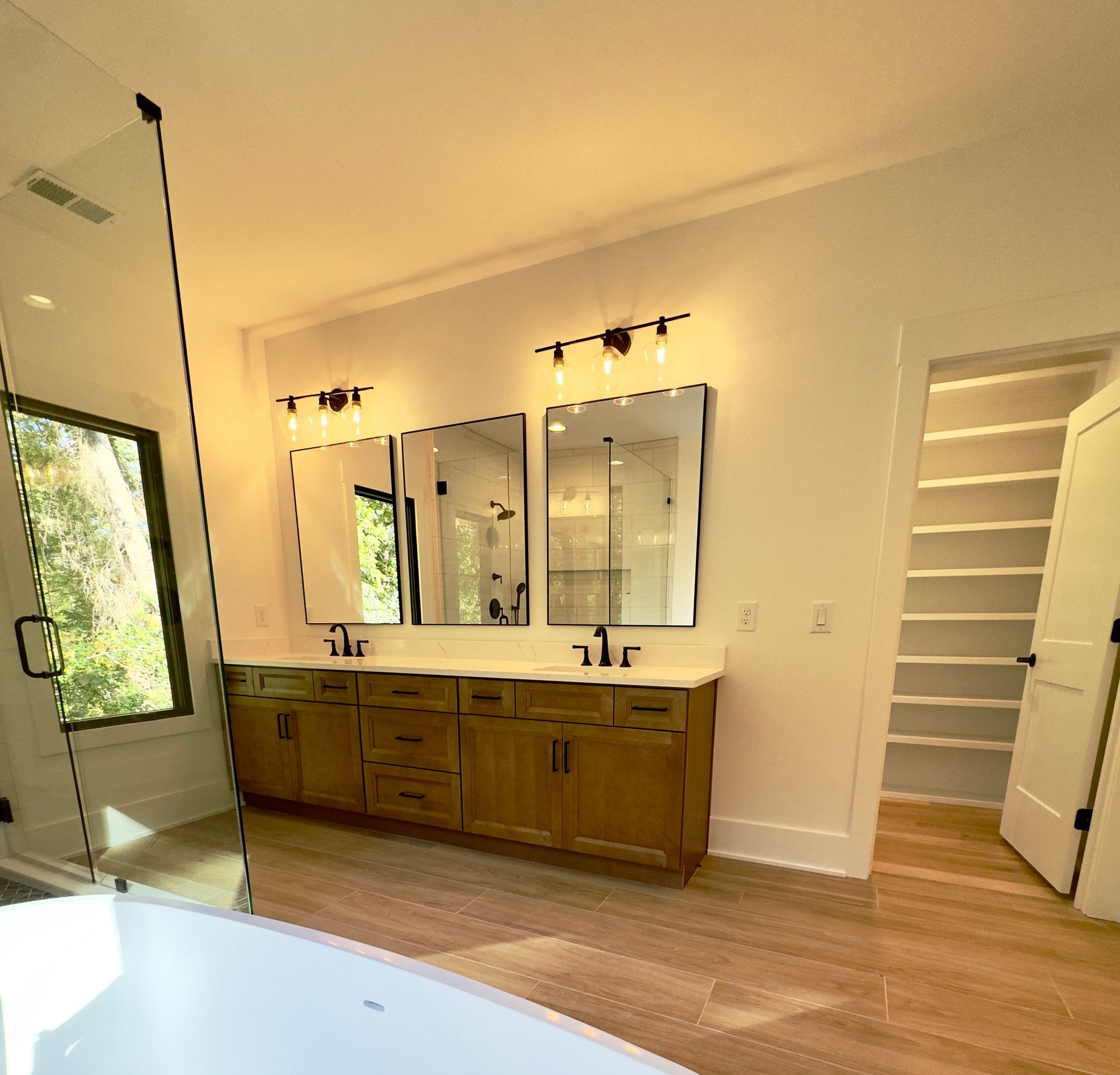 Bathroom with double vanity, mirrors, and a walk-in closet with shelves.