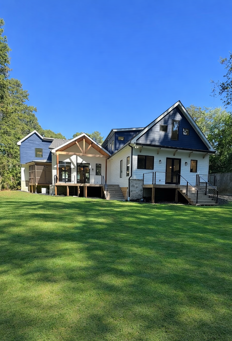 House under construction with blue and white siding, unfinished decks, and a clear blue sky.