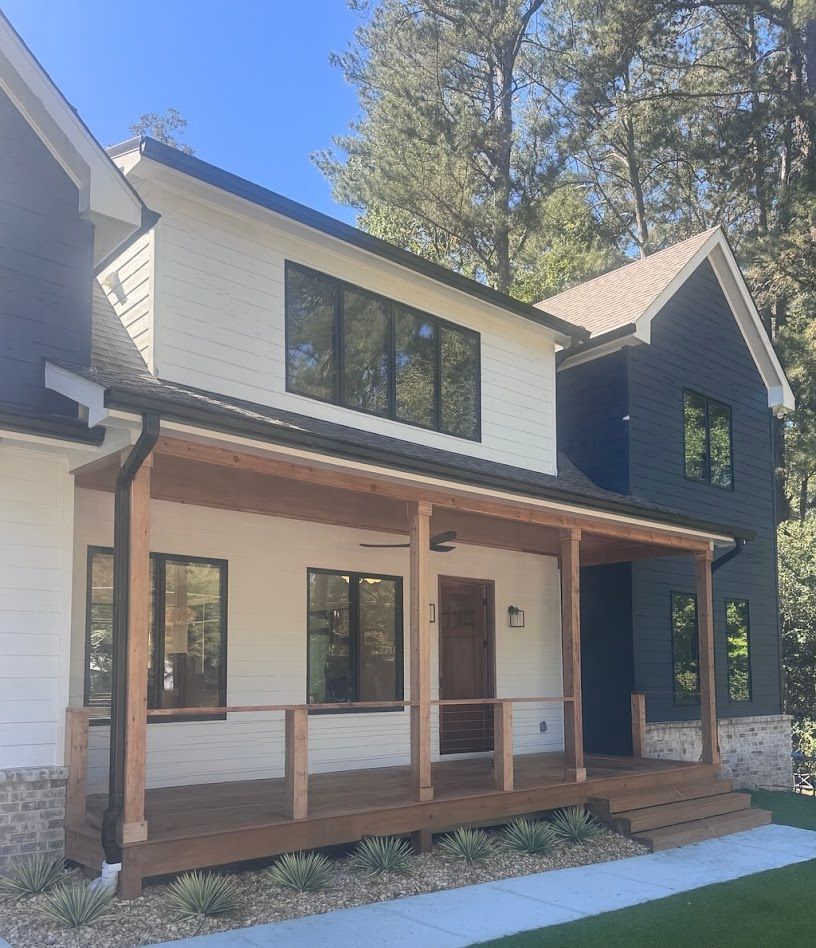 Modern two-story house with white and navy siding, a wooden porch, and black window frames.