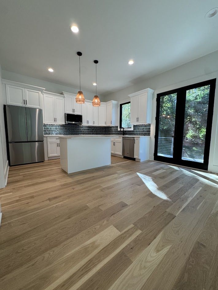 Bright kitchen with white cabinets, stainless steel appliances, wood floors, and French doors.