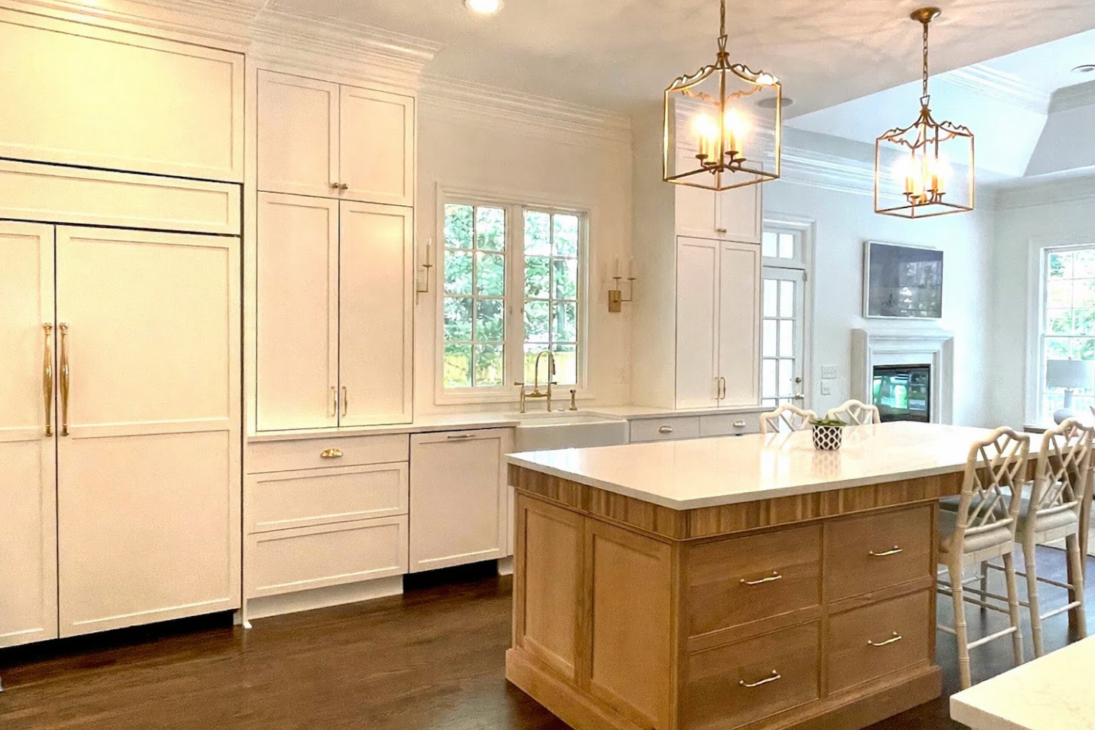 Elegant white kitchen with wood island, marble countertops, and pendant lights.