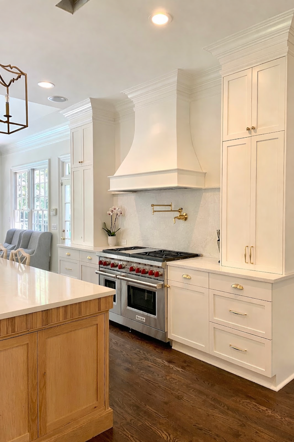 White kitchen with stainless steel appliances, dark wood floors, and a light-colored island.