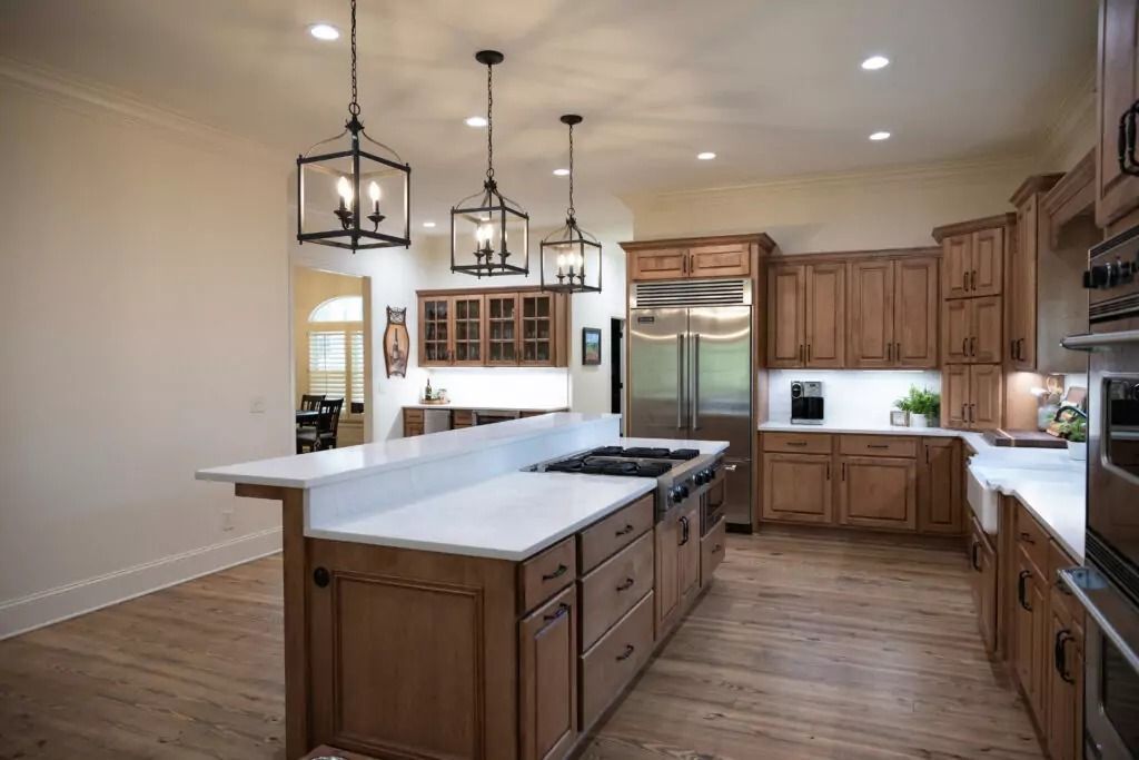 Spacious kitchen with a large island, wooden cabinets, stainless steel appliances, and hanging lanterns.