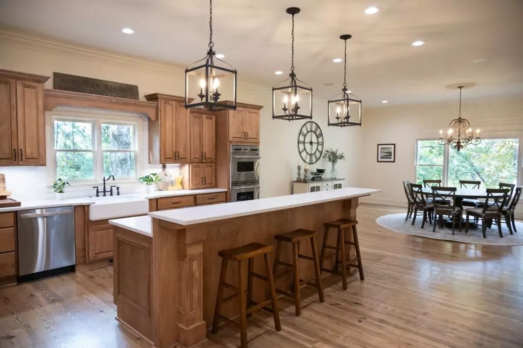 Spacious kitchen with wood cabinets, island, and dining area, lit by pendant lights.