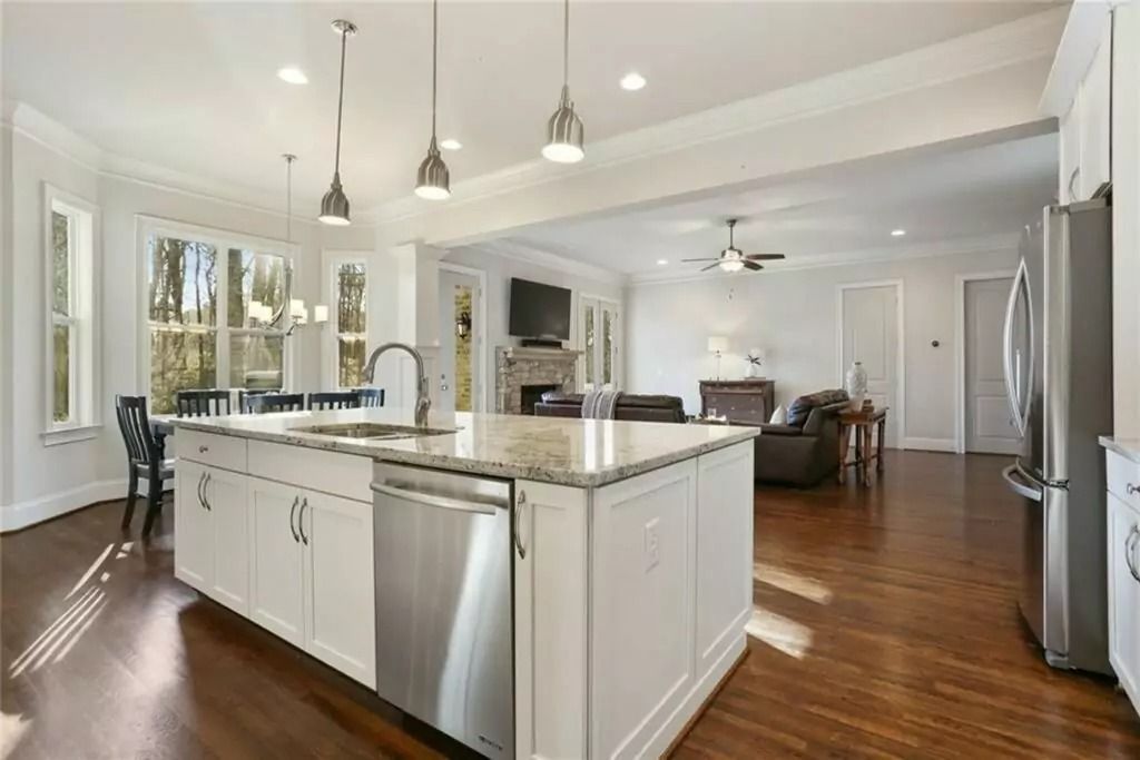 Spacious kitchen with island, stainless steel appliances, and adjacent living room with fireplace.