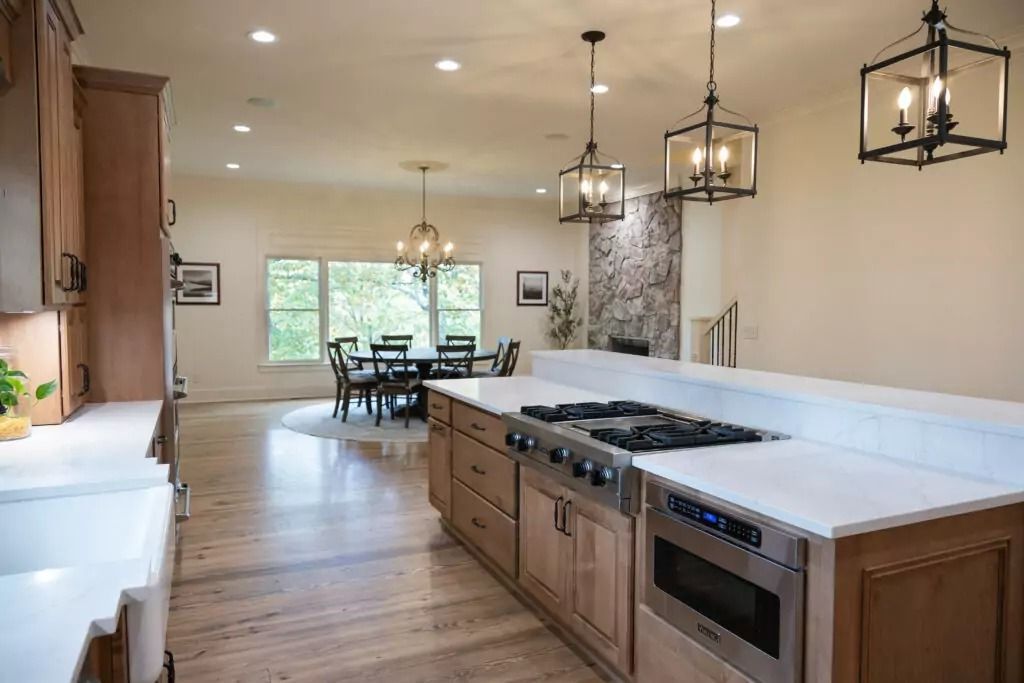 Spacious kitchen with island, range, and cabinets. Dining area with table and chairs.  Bright natural light.