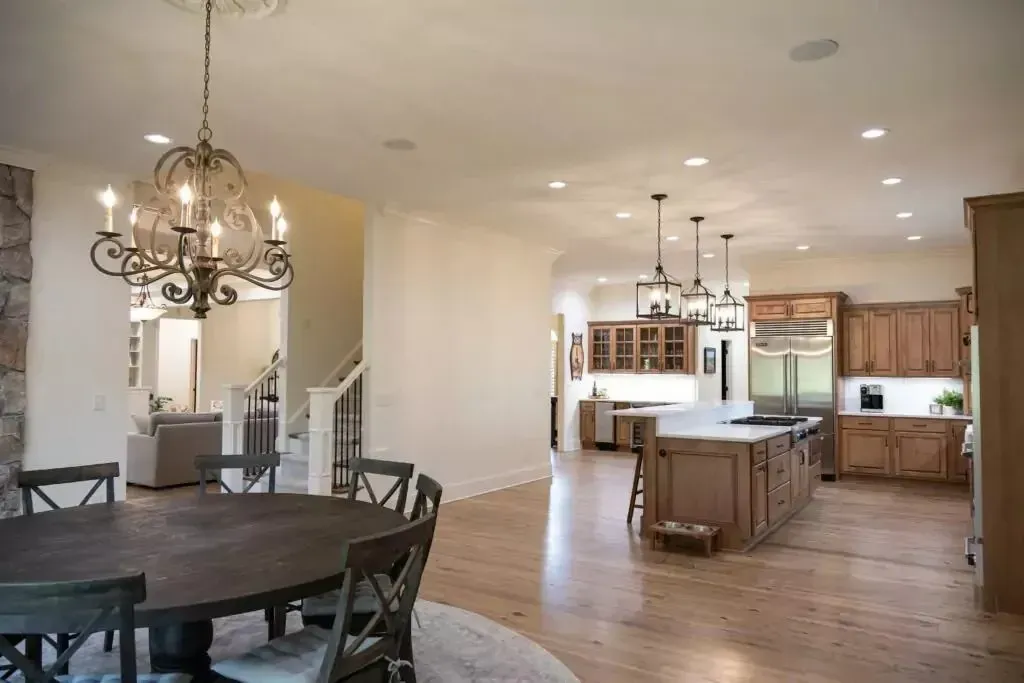 Open-concept kitchen and dining area with chandelier, wooden cabinets, and island.
