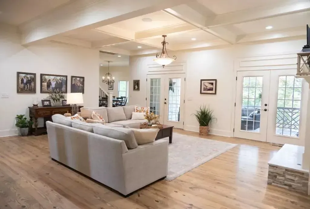 Spacious living room with light wood floors, large sectional sofa, and French doors leading outside.
