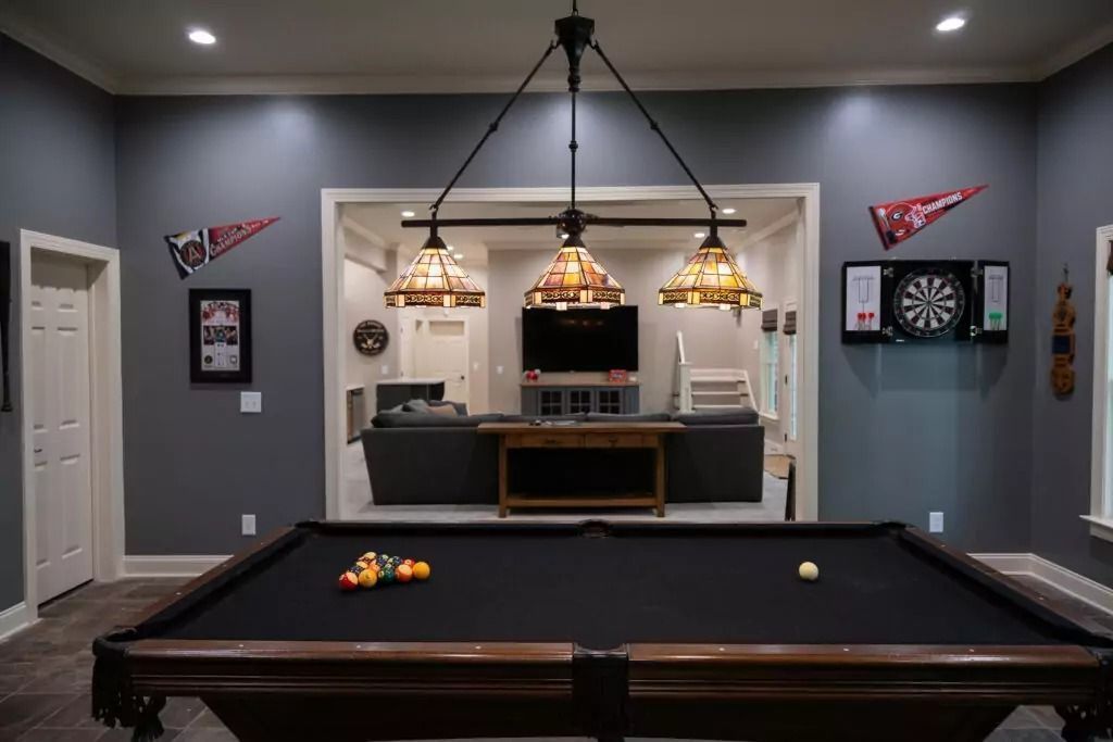 Pool table in a game room with dark walls and three hanging lamps.