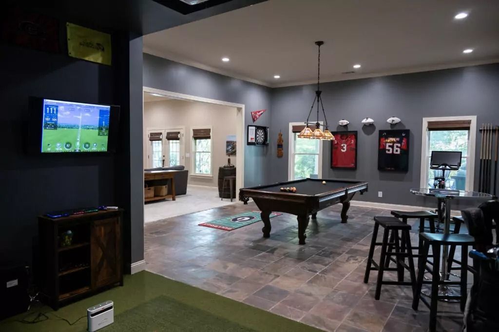 Game room with pool table, bar stools, TV, and sports memorabilia.